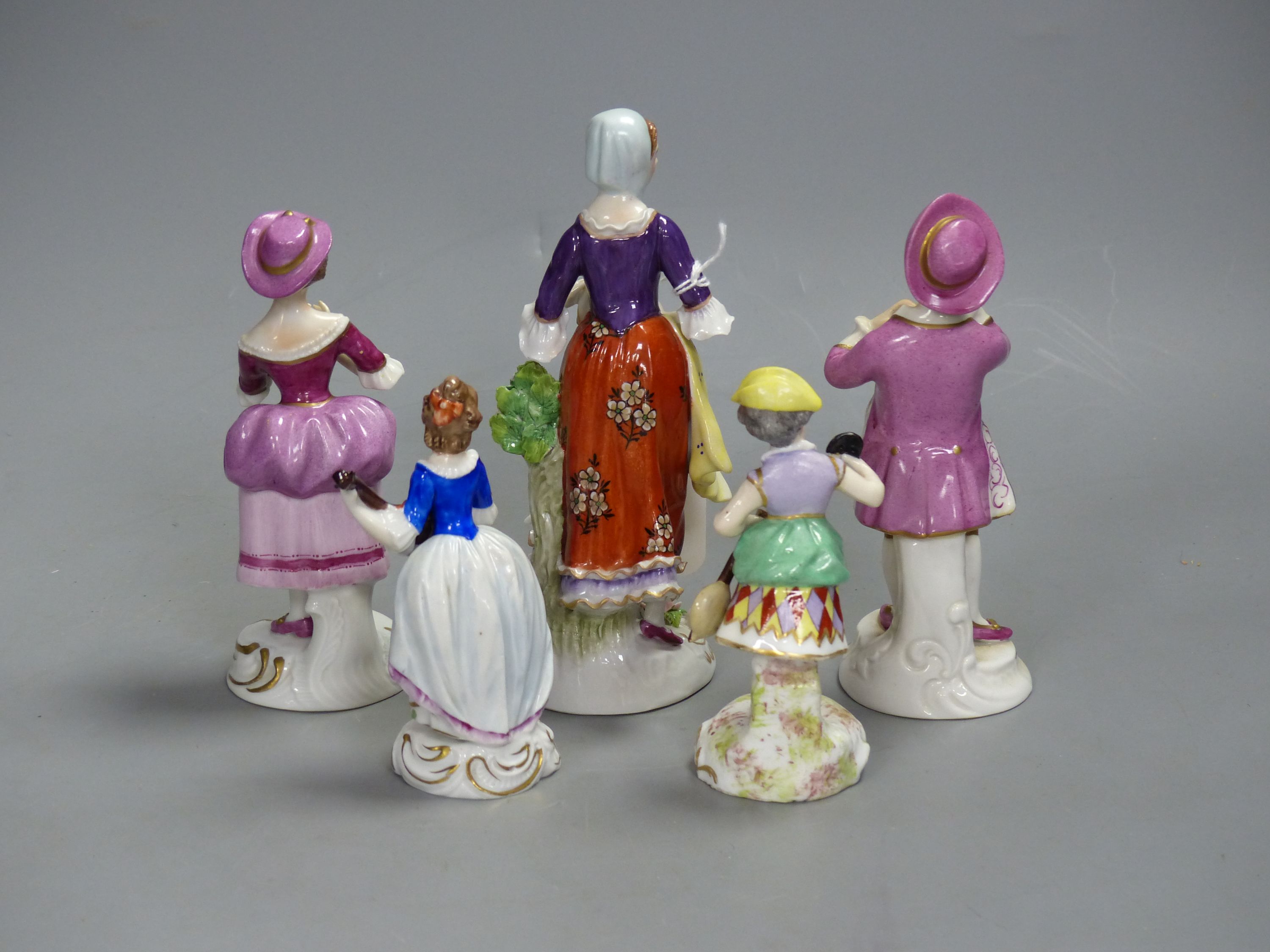 A German porcelain figure of a masked harlequin with stringed instrument and four other Continental porcelain figures, tallest 16cm